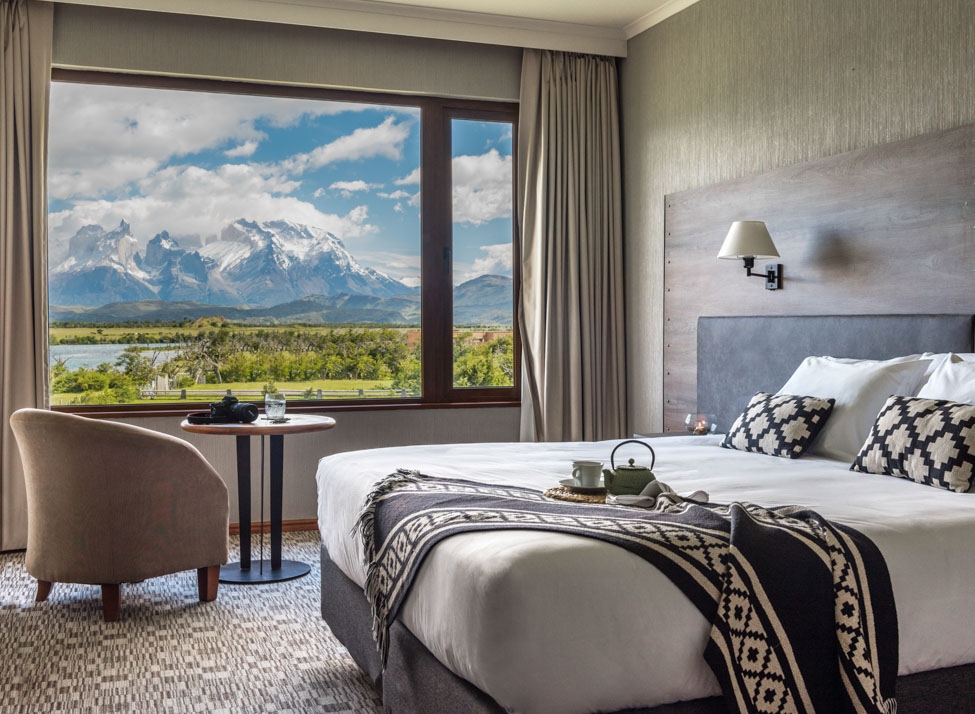Bedroom at Kau Rio Serrano lodge with a view of mountains of Patagonia outside.