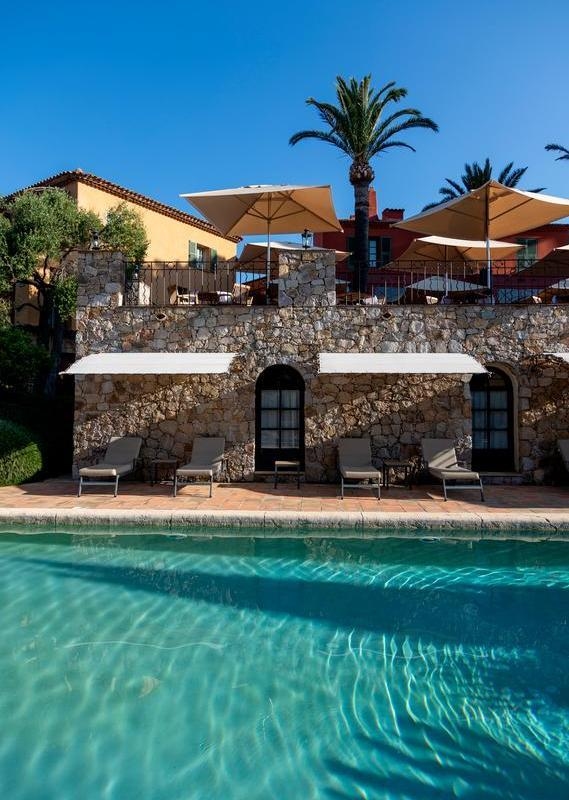 A swimming pool with a stone building and palm trees behind it