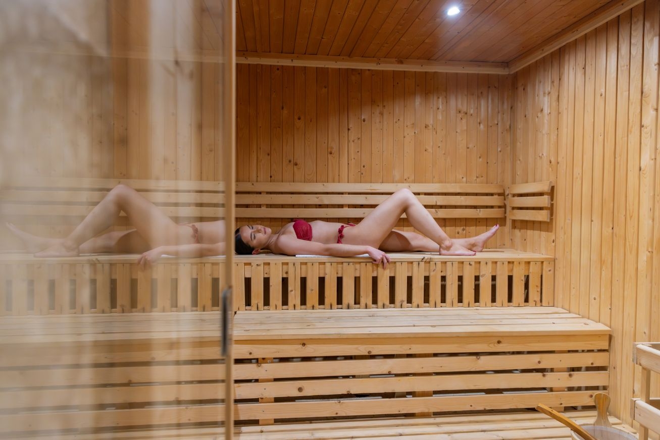 A woman in a red bikini lying on her back in a wood sauna