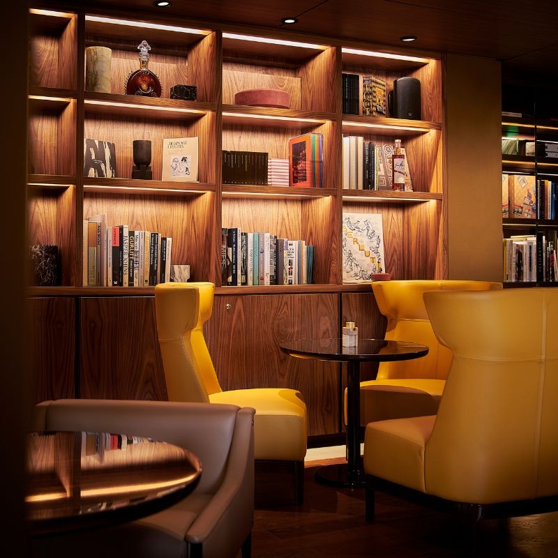 A dimly lit sitting area with yellow chairs and bookshelves
