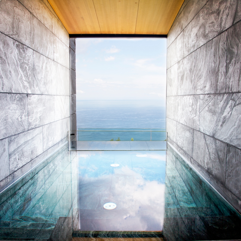 Interior of a plung swimming pool with a square infinity window overlooking the sea.