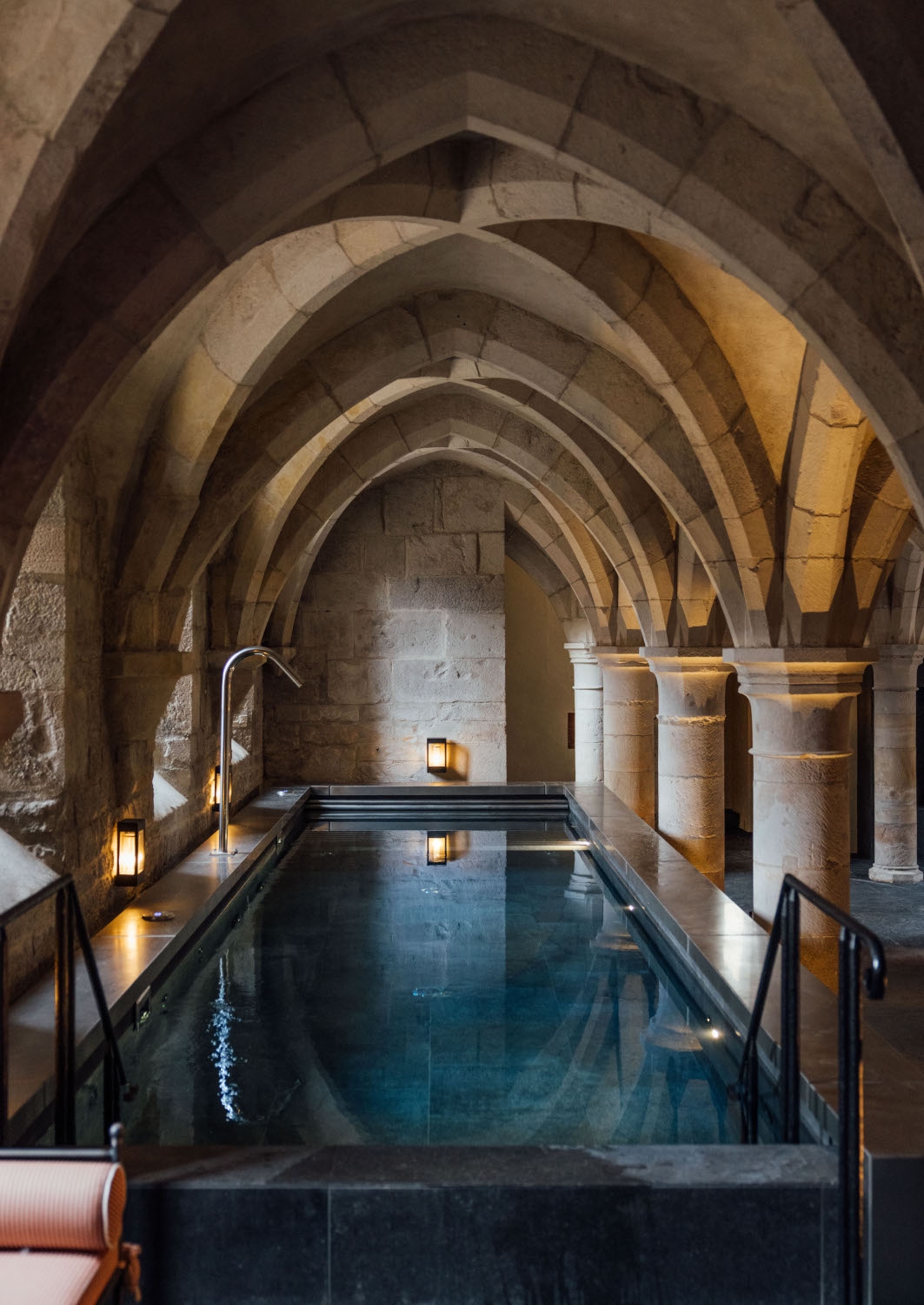 Historic vaulted chamber with a long, rectangular swimming pool down the middle.