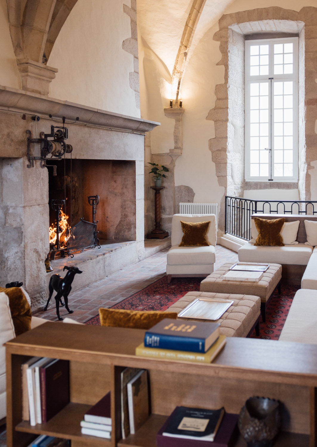 Interior of the hotel receiption with historic stone walls and white sofas around a lit fireplace