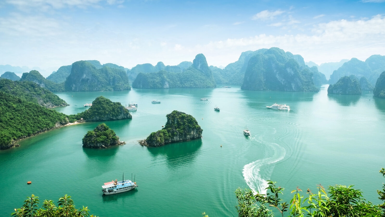 High-angle view of green limestone karsts and islands scattered across the turquoise waters of Ha Long Bay, Vietnam.