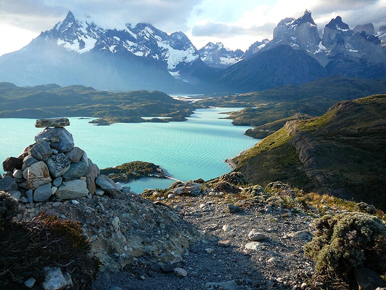 A rocky overlook of a bright blue lake and jagged mountains on luxury Chile trips.