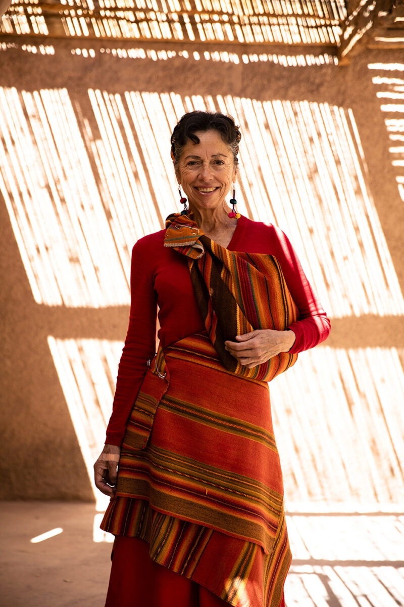 A woman smiling in traditional colorful Andean clothing, experienced on luxury Chile holidays.