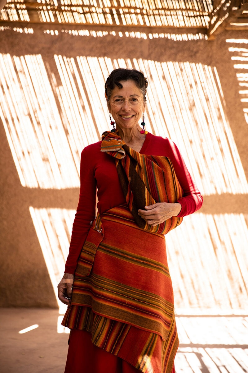 A woman smiling in traditional colorful Andean clothing, experienced on luxury Chile holidays.