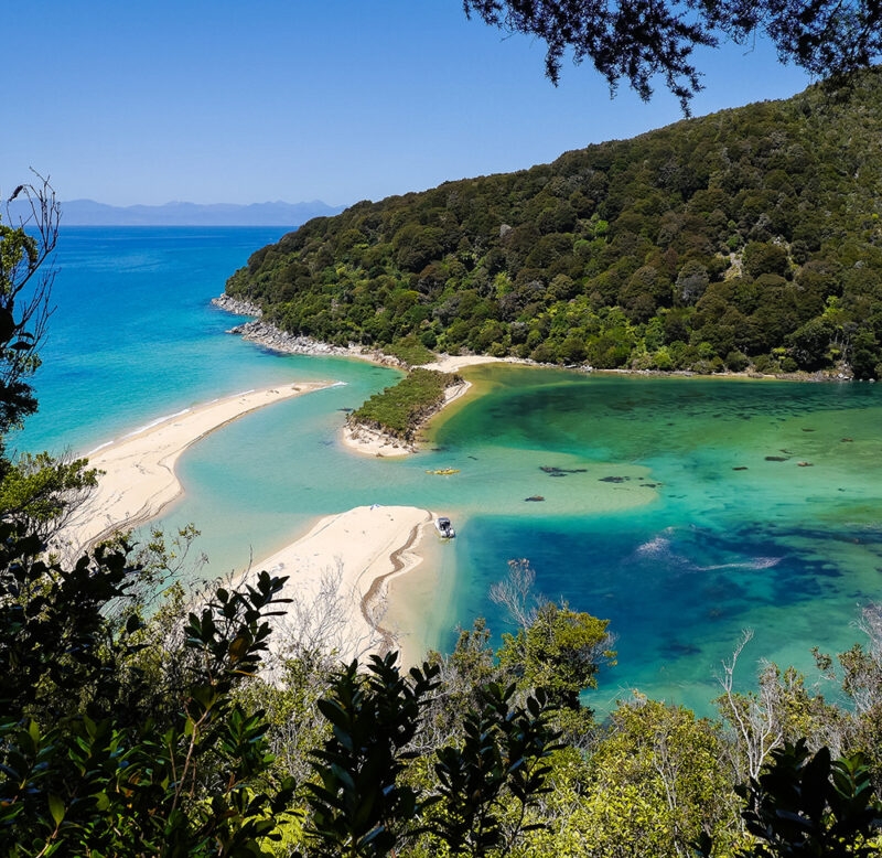 Aerial view of a turquoise lagoon and golden sand beaches during luxury New Zealand tours.