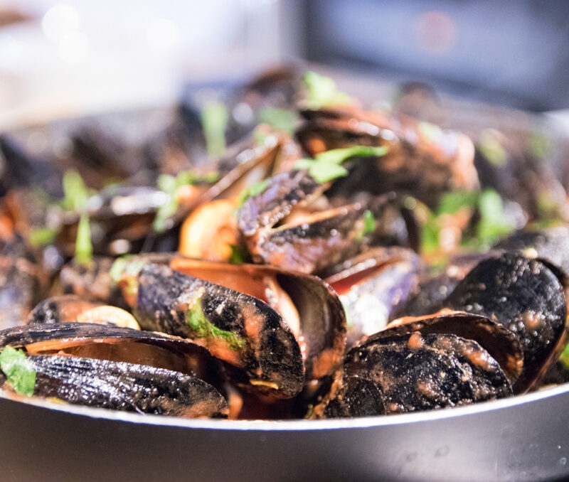 Close-up of cooked mussels in shells with herbs, representing the cuisine of luxury Croatia tours.