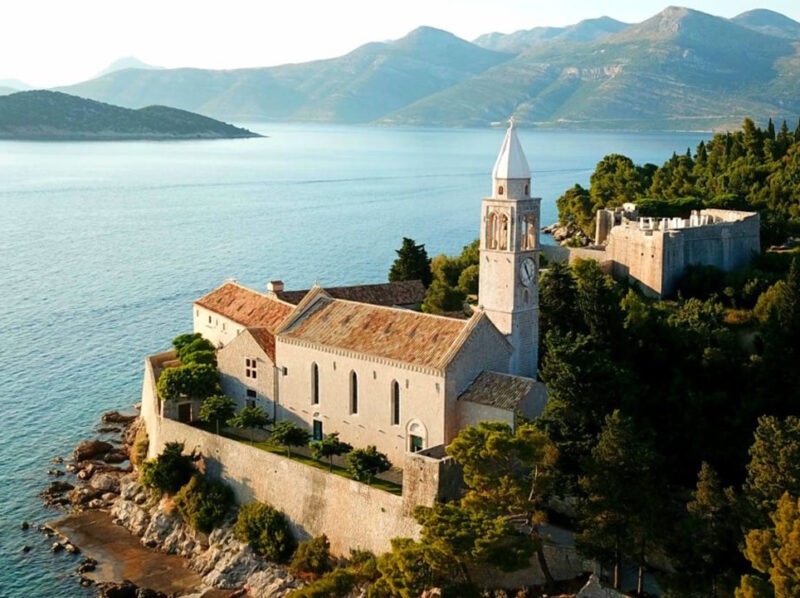 Stone monastery and bell tower on a rocky coast above the Adriatic Sea for luxury Croatia holidays.