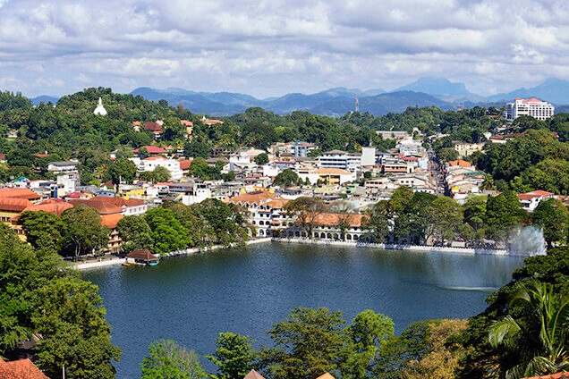Aerial view of a city lake surrounded by white buildings and green hills on luxury Indian Subcontinent tours.
