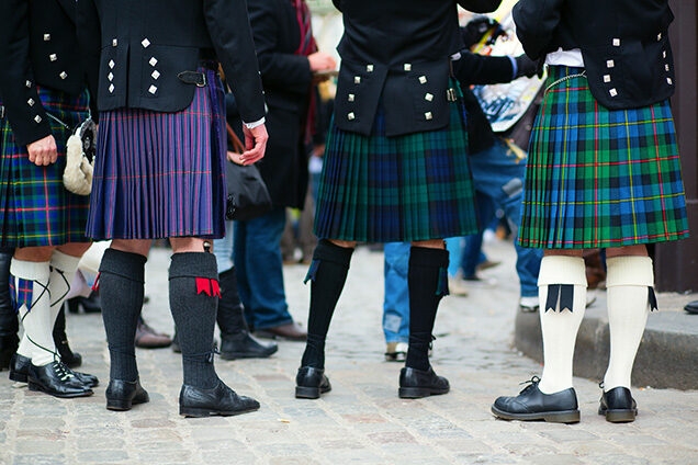 The lower half of men wearing traditional Scottish kilts and socks for luxury culture tours.