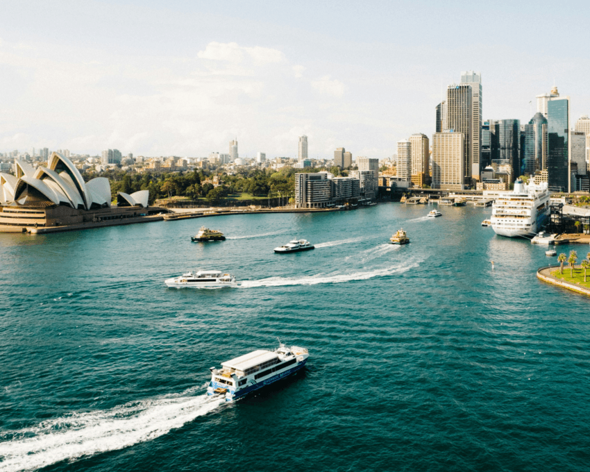 Sydney Harbour and city skyline, with ferries and small boats leaving the quayside, and the Opera House visible
