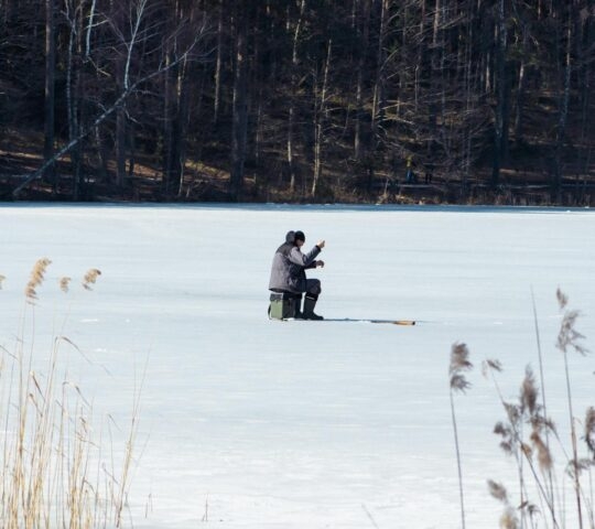Fisherman fishing on a frozen lake in Finnish Lapland