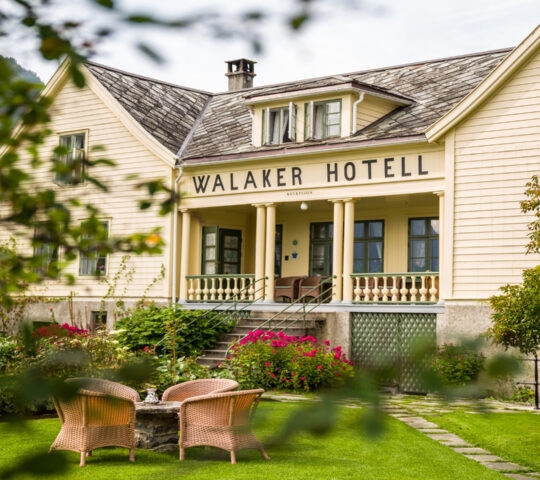 Charming Walaker Hotel with garden and wicker chairs in front.