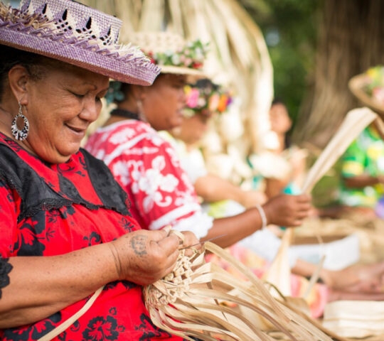 Women in traditional clothing handcrafting baskets outdoors.