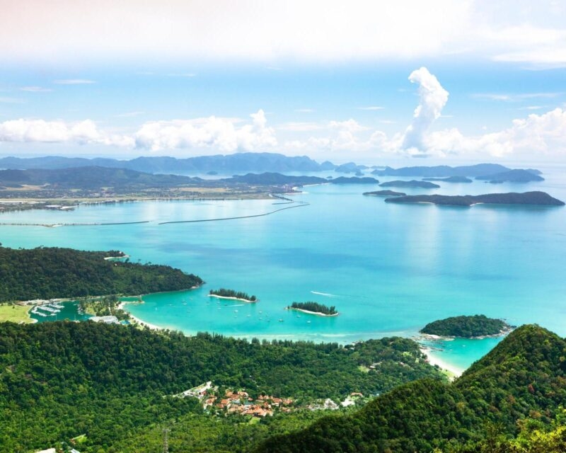 Aerial view of a tropical coastline with turquoise waters, islands, and a lush green landscape.