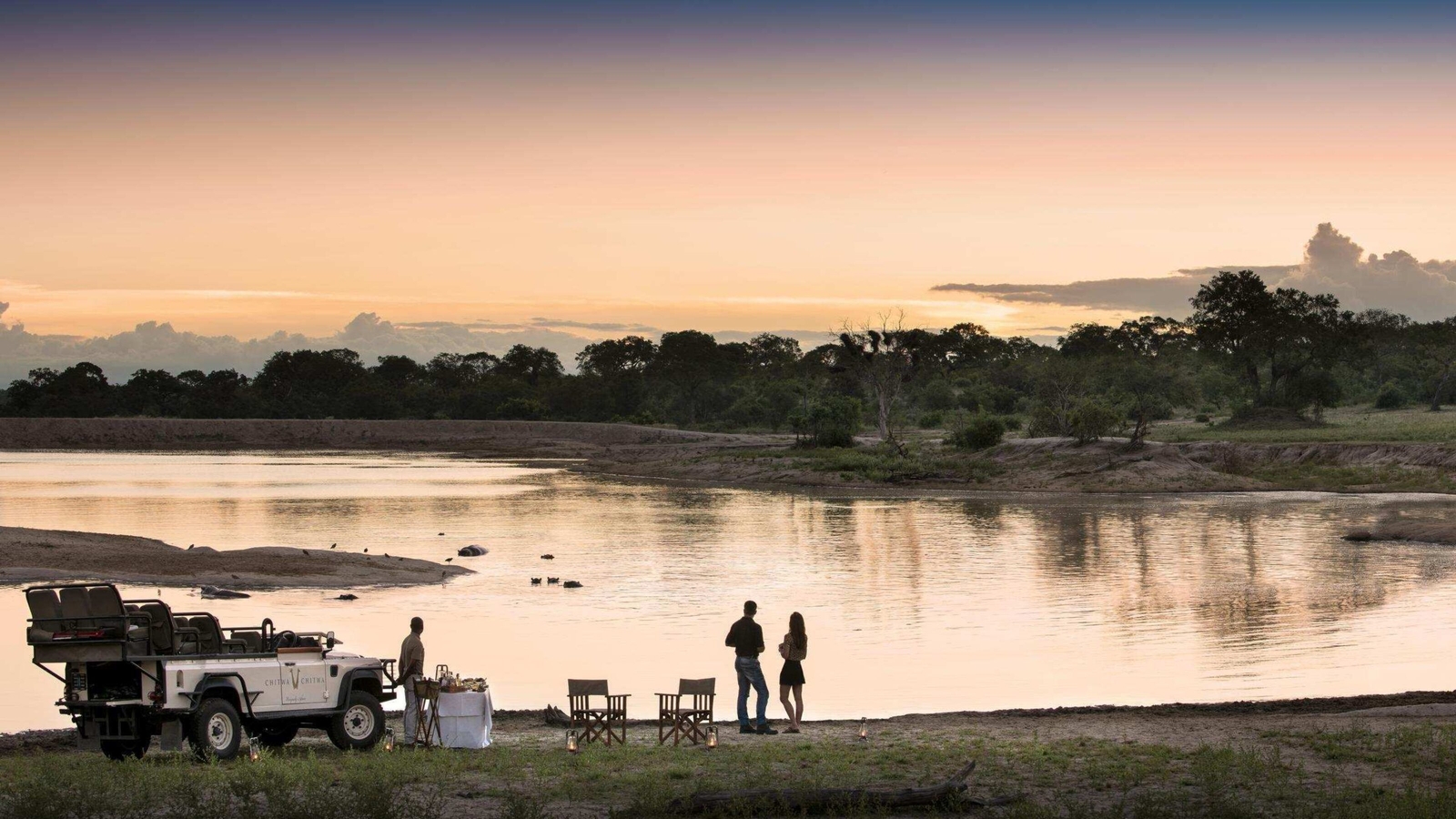 A couple participating in sundower drinks by a body of water.