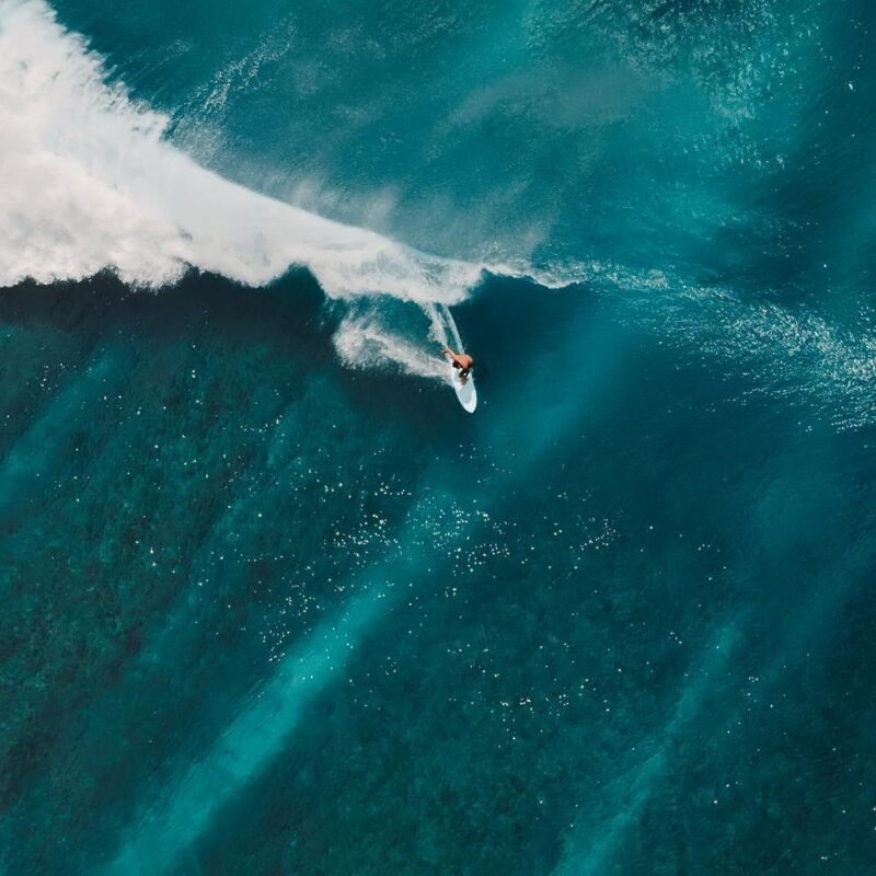 Aerial view of a man surfing on turquoise waves