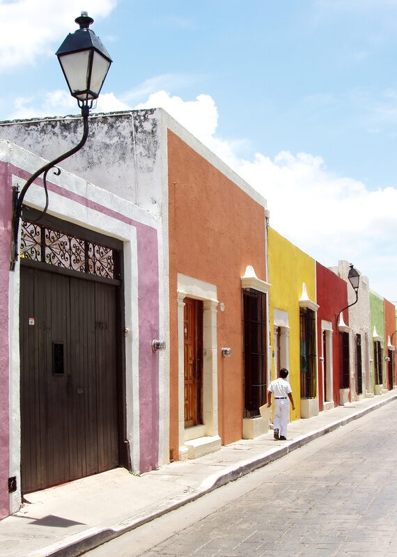 A man walks down a street of colourful houses in Mérida, Mexico
