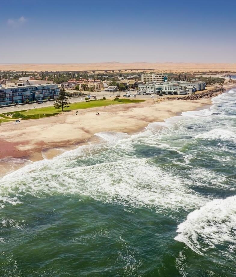 A coastal town next to a sandy beach and crashing waves on Namibia and Botswana Luxury Tours.
