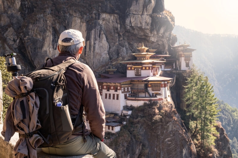 tourist sitting on his back watching tiger`s nest temple Paro