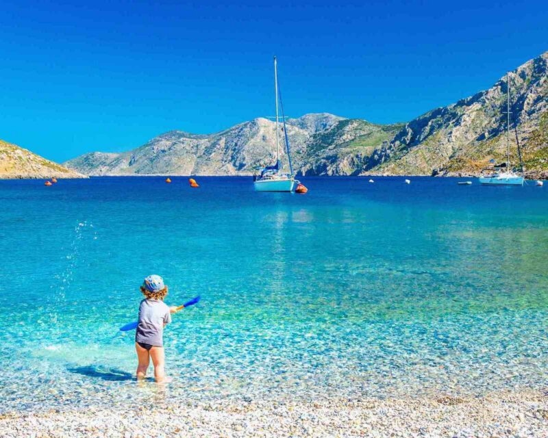 Amazing sea bay on Greek Island with a small boy at play on the seashore Greece