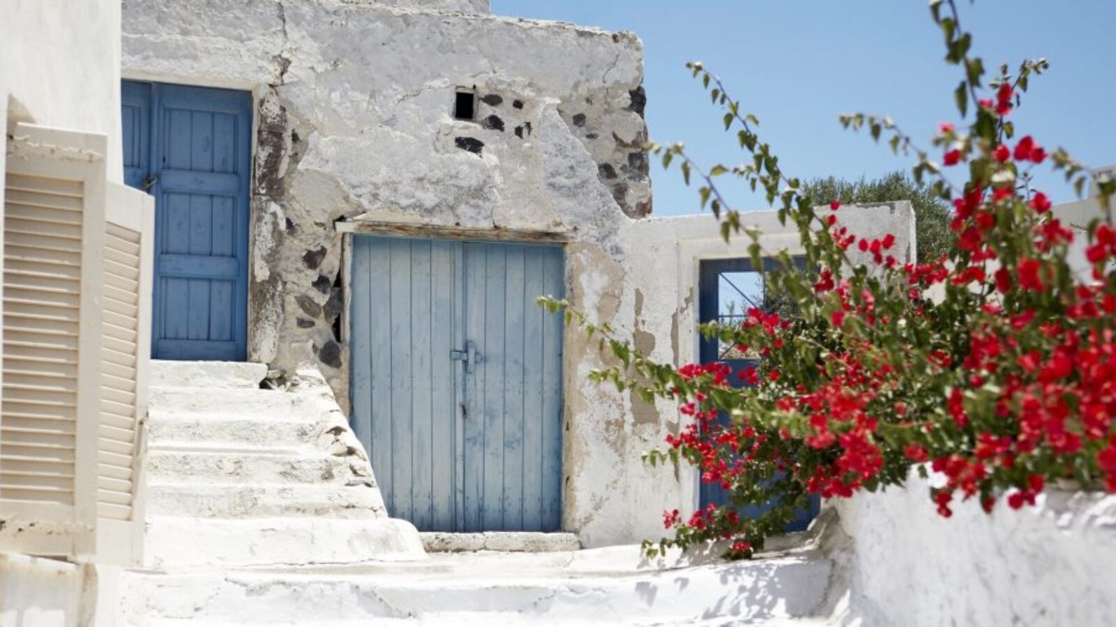 Luxury Greece Tours - Red bouganvellia set against whitewashed stone building with blue wooden doors