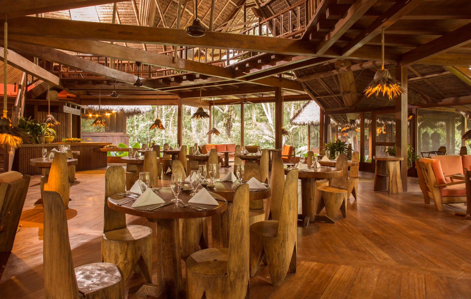 Rustic dining room with wooden furniture and tropical forest view through large windows.