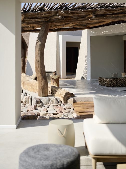 Modern concrete patio with a rustic wood pergola, lounge seating, and a view of a rocky desert.