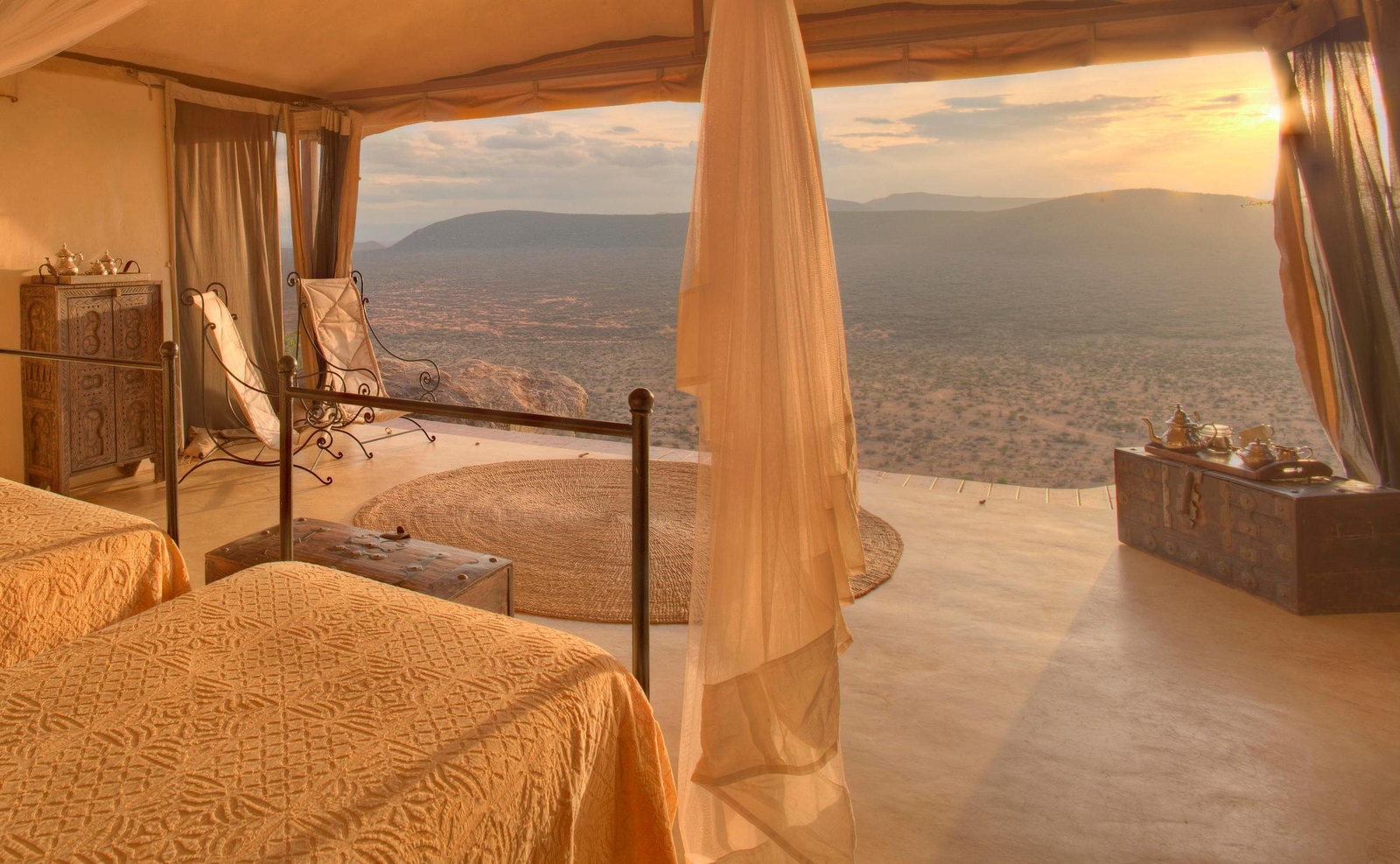 Two twin beds with mosquito nets in an open-fronted room overlooking the vast plains of Saruni Samburu.