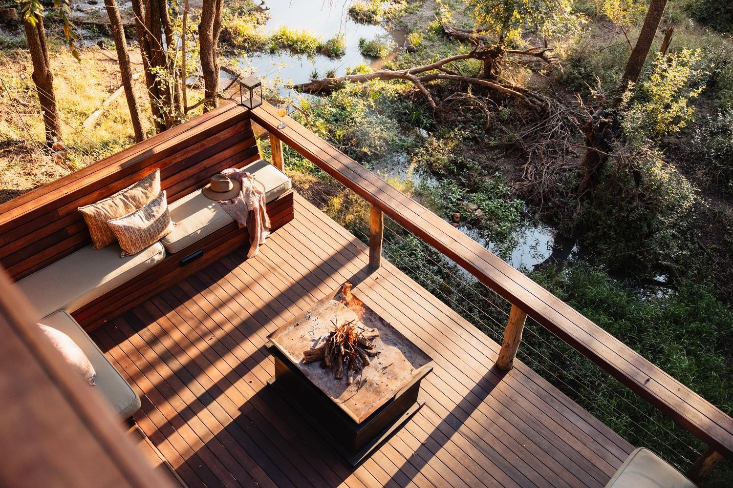 Wooden deck at Jaci's Private Lodge with corner seating and a fire pit overlooking a small natural waterhole.