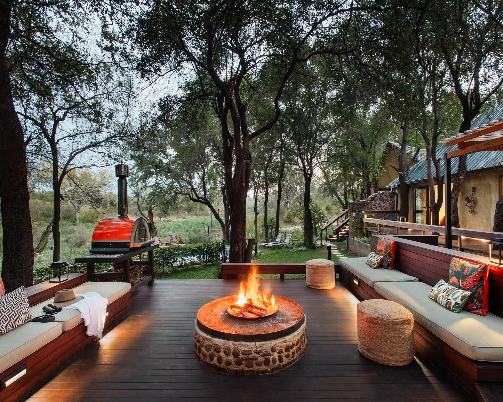 Interior lounge at Jaci's Private Lodge showing a central fireplace, seating, bar, and wooden ceiling.