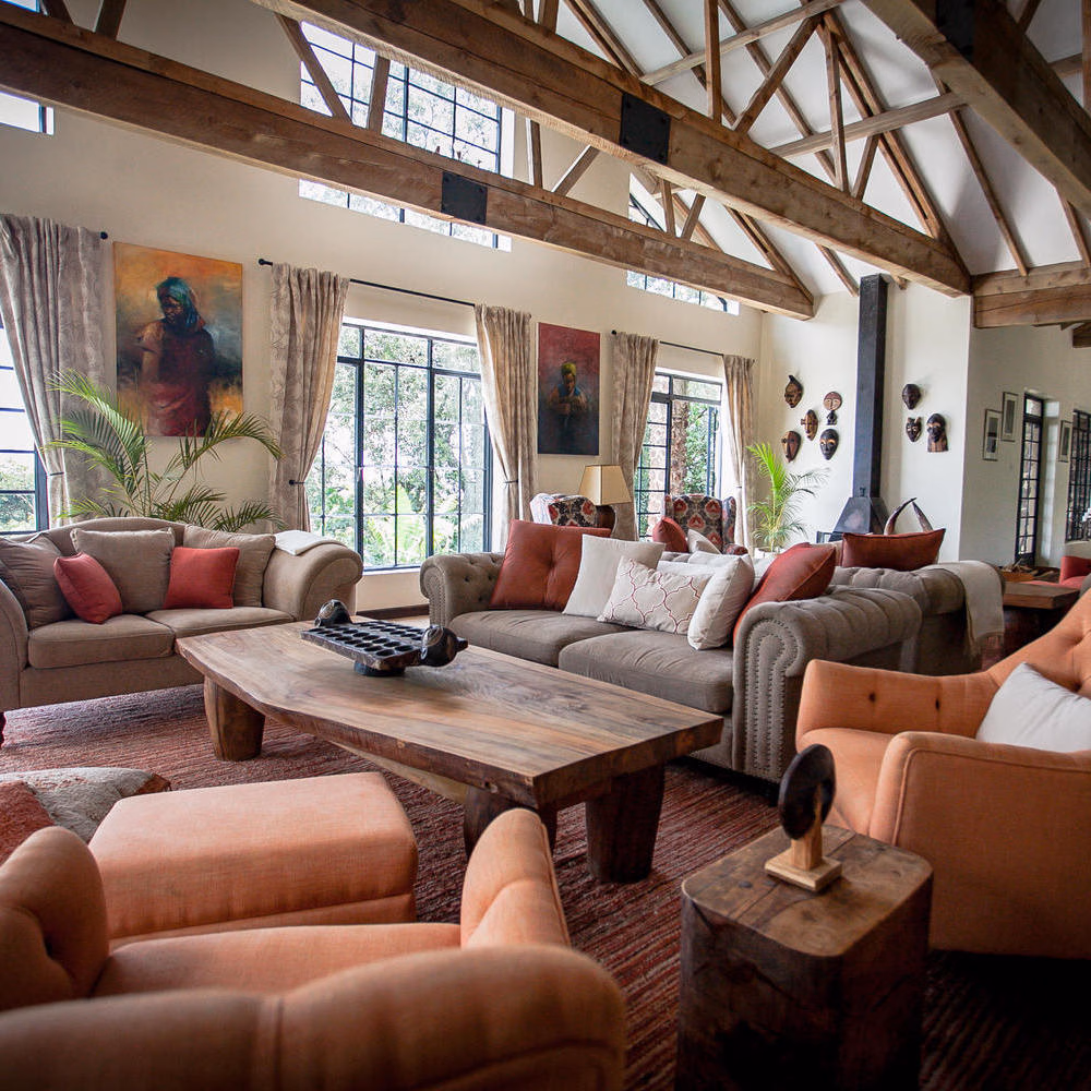 Lounge at Clouds Lodge Uganda featuring comfortable seating, a live-edge wooden table, and African masks.