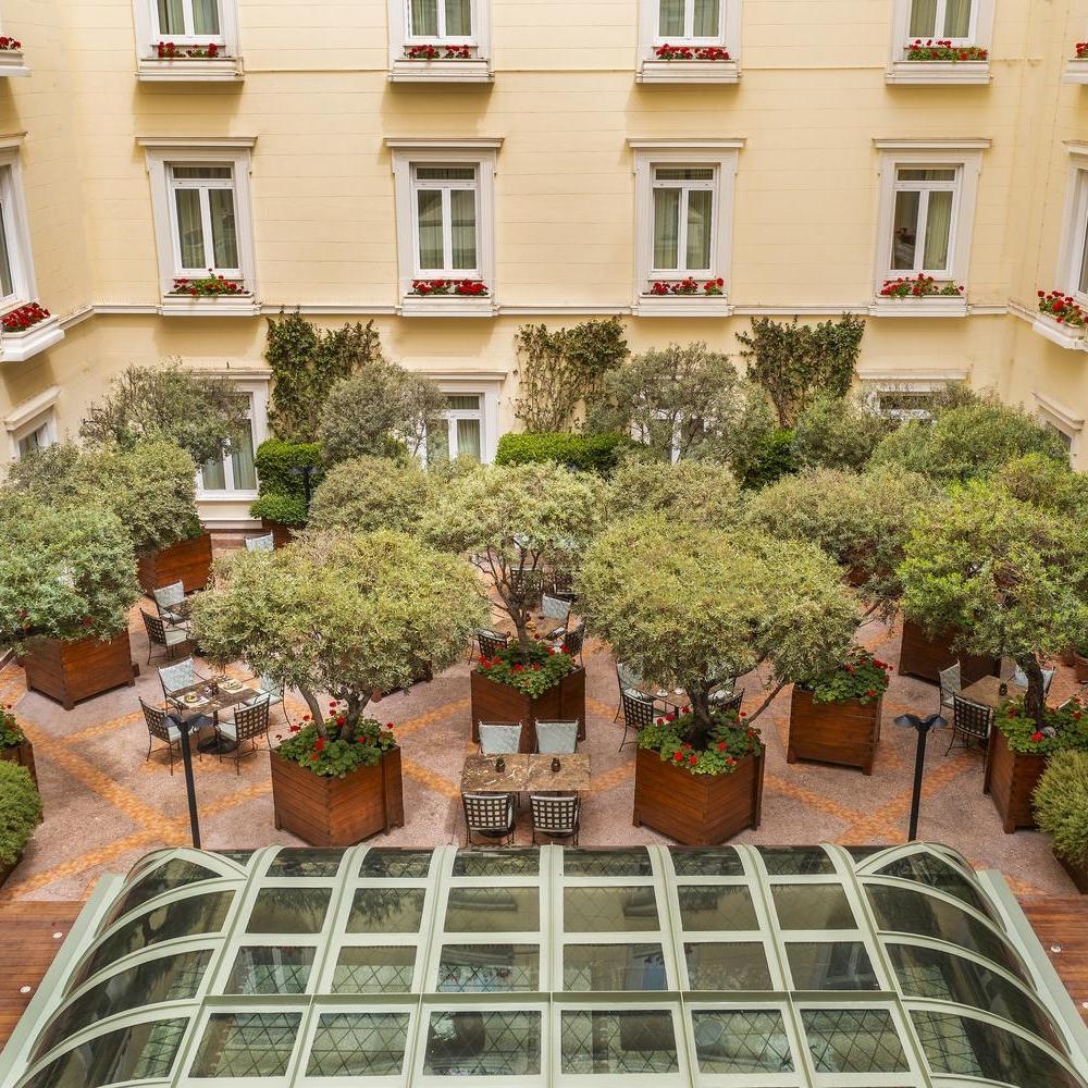 An inner courtyard with tables and trees at Hotel Grande Bretagne