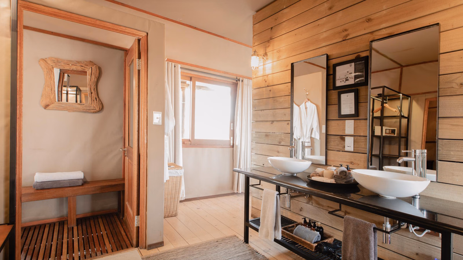 Rustic bathroom interior with a double vanity, white vessel sinks, mirrors, and an open doorway leading to a wooden shower.