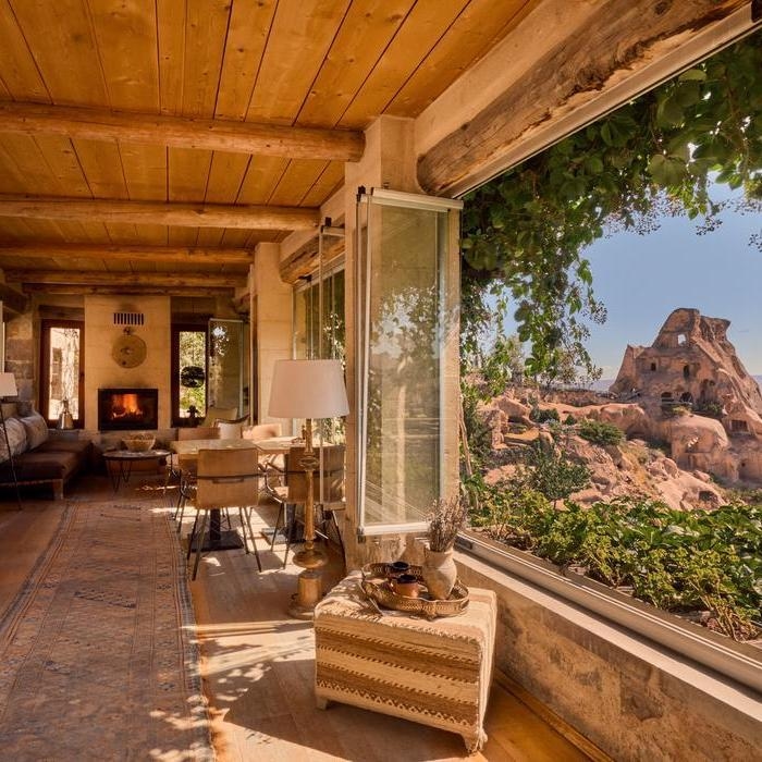 An indoor seating area with wooden beams and a large window looking out at a rock structure.