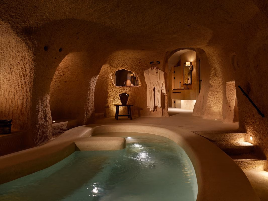 A dimly lit indoor pool carved into a stone cave with warm ambient lighting.