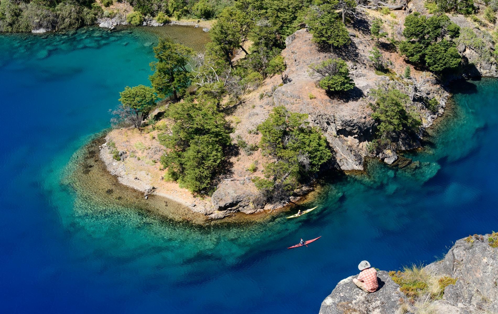 Aerial view of two kayakers in vibrant blue water near an island at Explora Patagonia National Park.