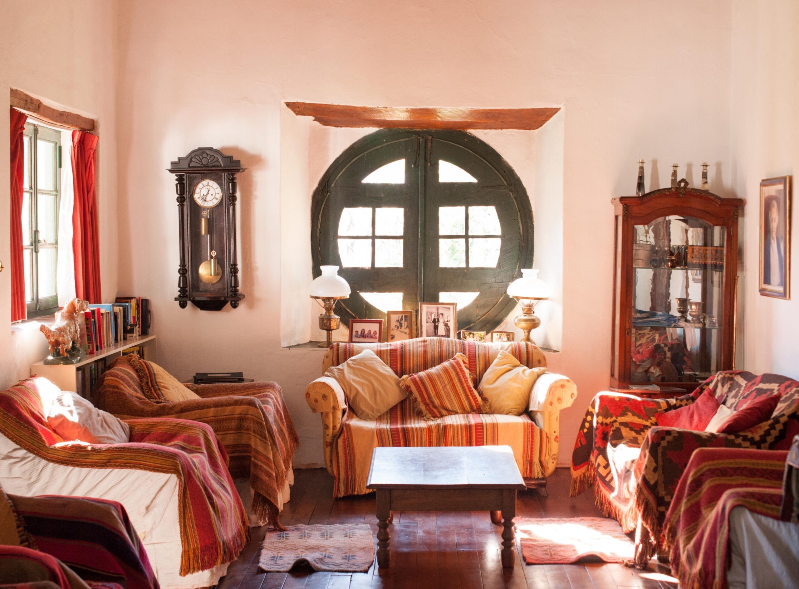 Cozy living room with colorful blankets, wooden furniture, and a large window.