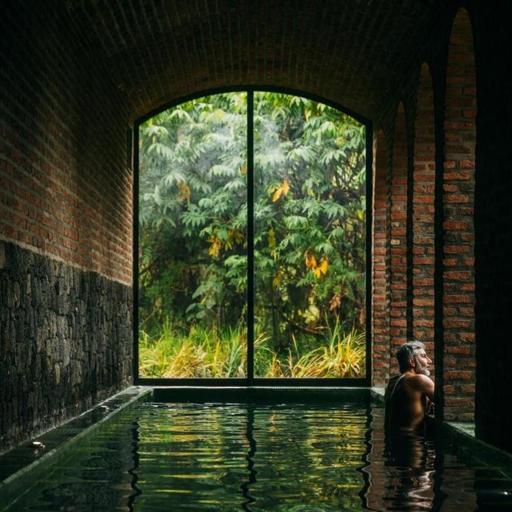 Man looking out the window from the spa pool at The Sanctuary spa at Wilderness Bisate, Rwanda