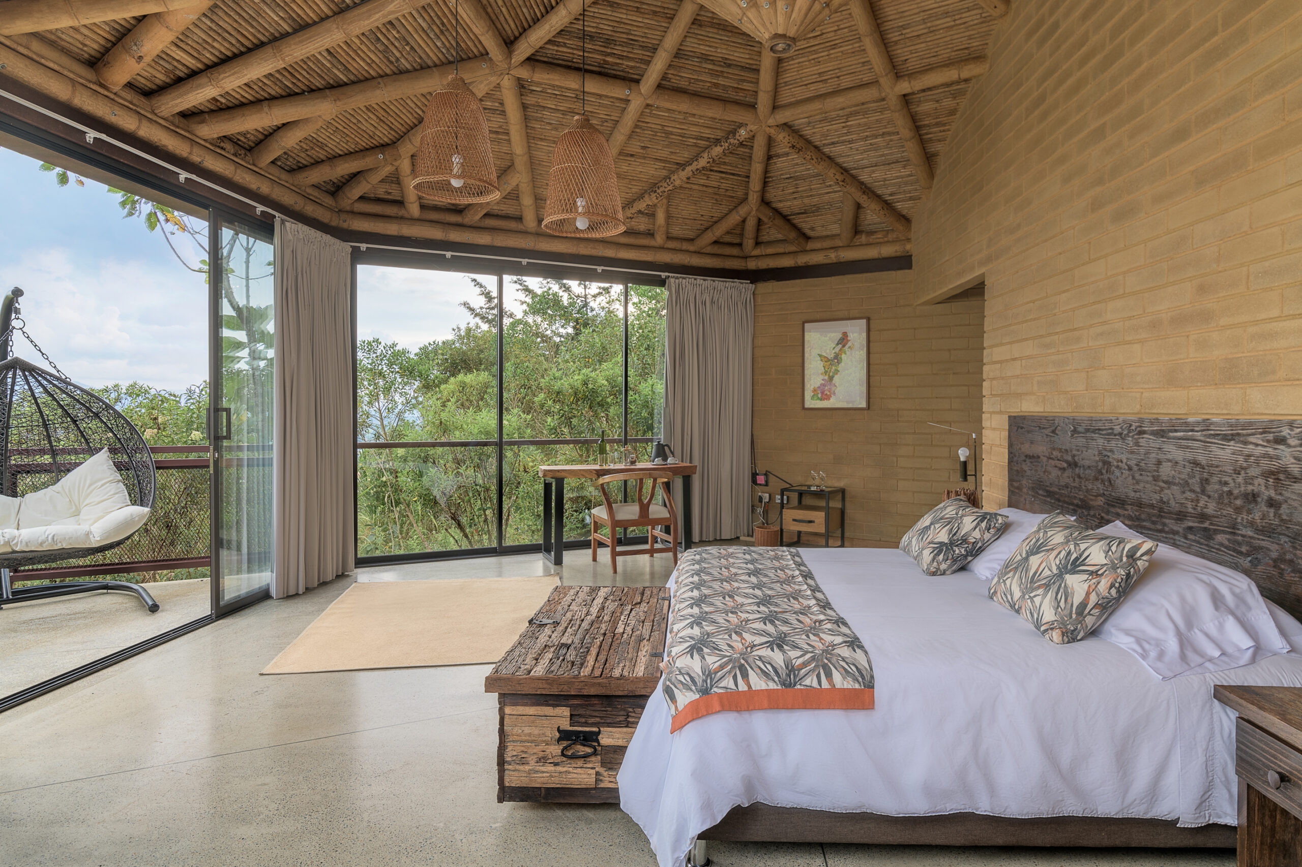 Rustic bedroom with a bed, hanging chair, and balcony overlooking a green landscape.