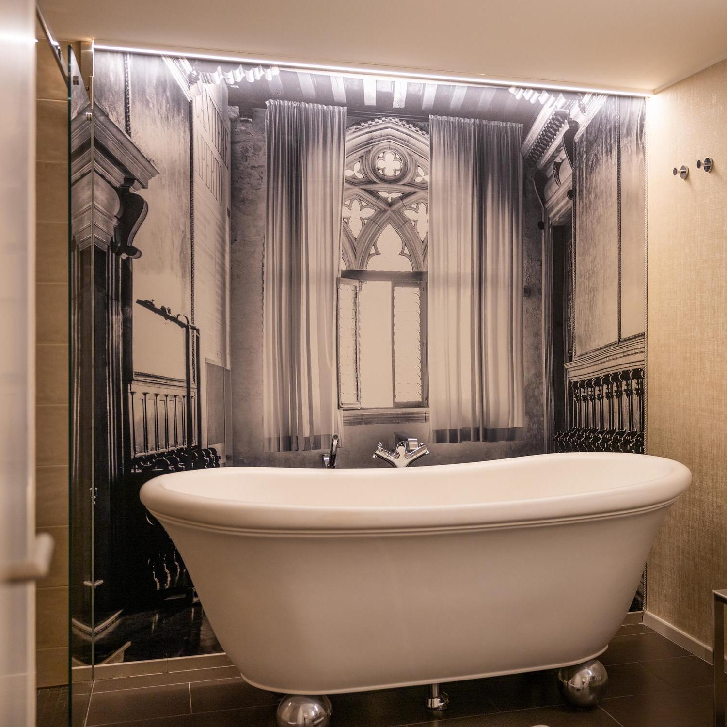 A vintage-style freestanding bathtub in a bathroom with a monochrome architectural mural.