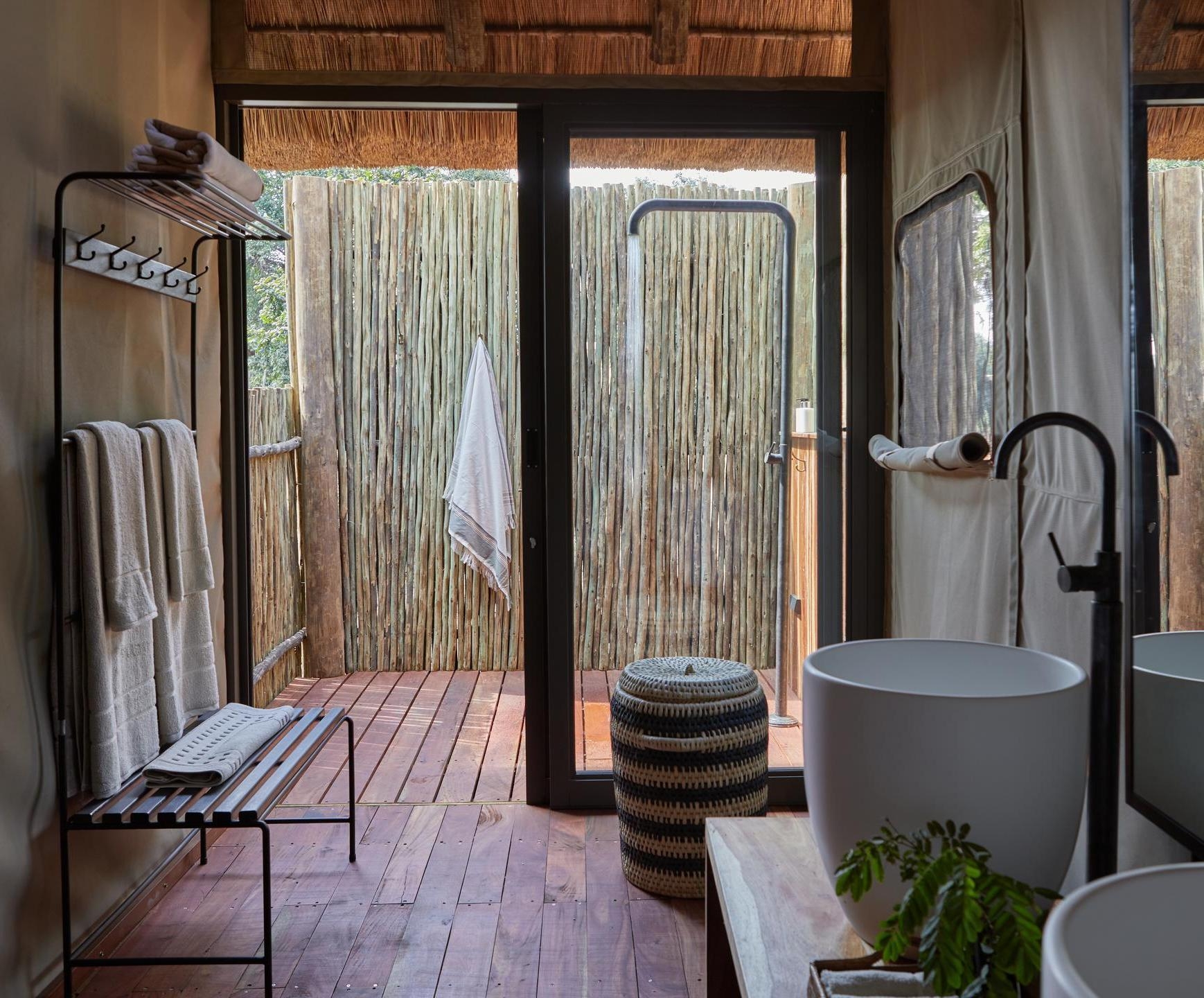 Rustic bathroom interior with wooden floor, open door, and outdoor shower area.