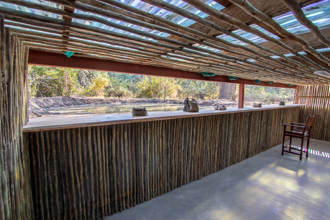 Rustic outdoor pavilion with wooden slats roof and a counter facing nature.