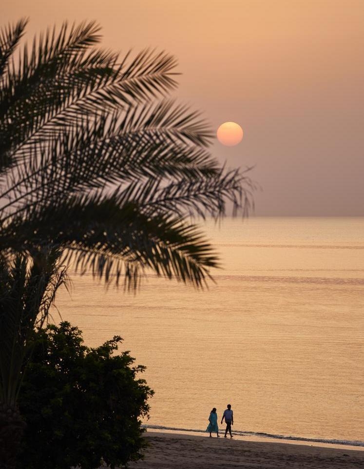 Couple strolling on a beach at sunset.