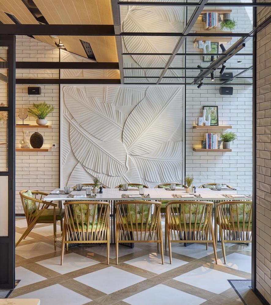 A restaurant at Mandarin Oriental Muscat, that's airy and bright with a neutral colour scheme. It's a glimpse of one long table surrounded by chairs with green cushions.