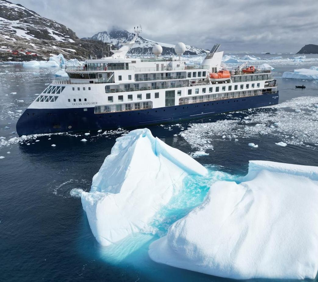 A view of the Ocean Explorer with an iceberg in the foreground.