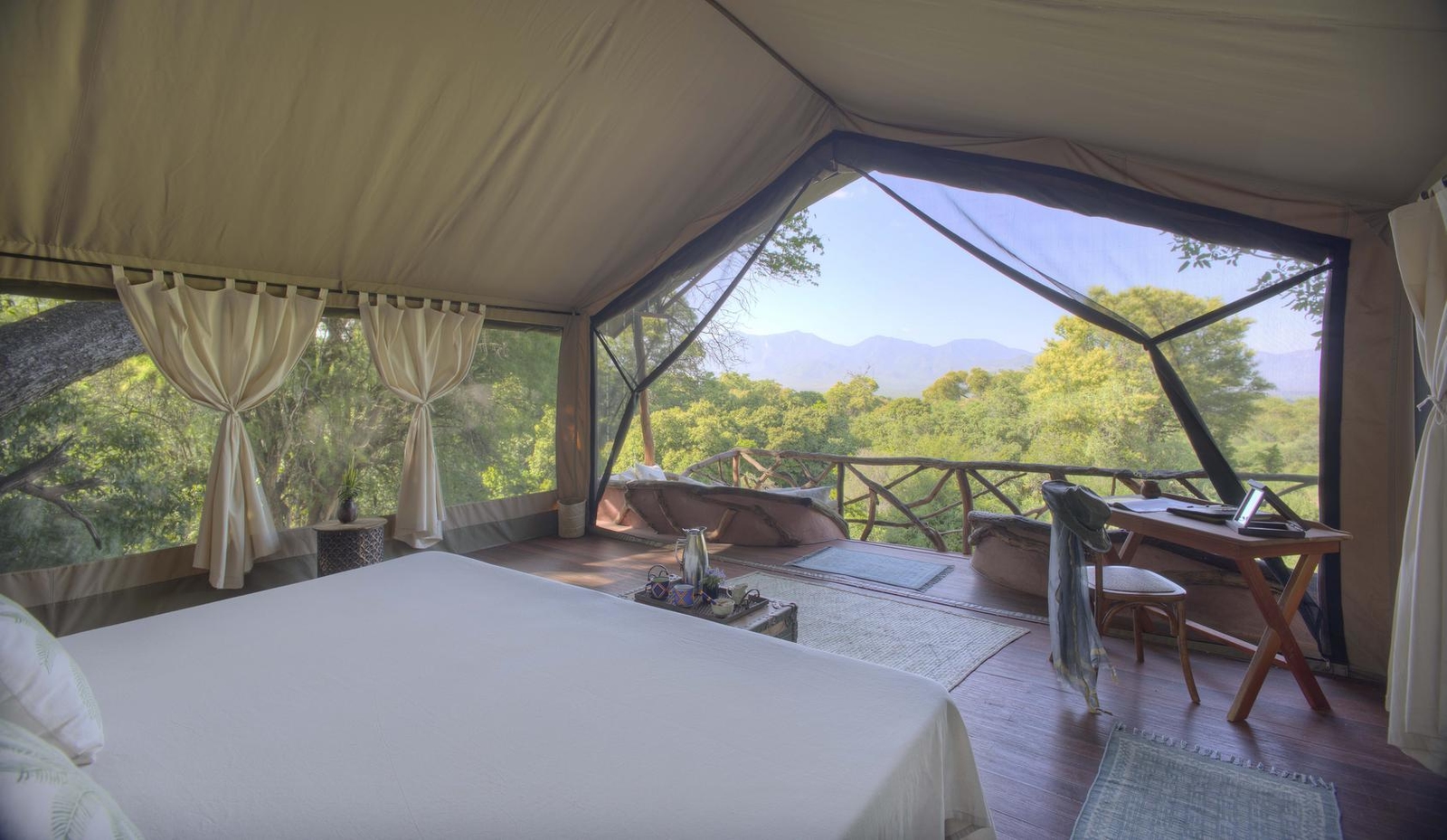 A view of the open-plan bedroom of a tent at Sarara Treehouses overlooking the forest.