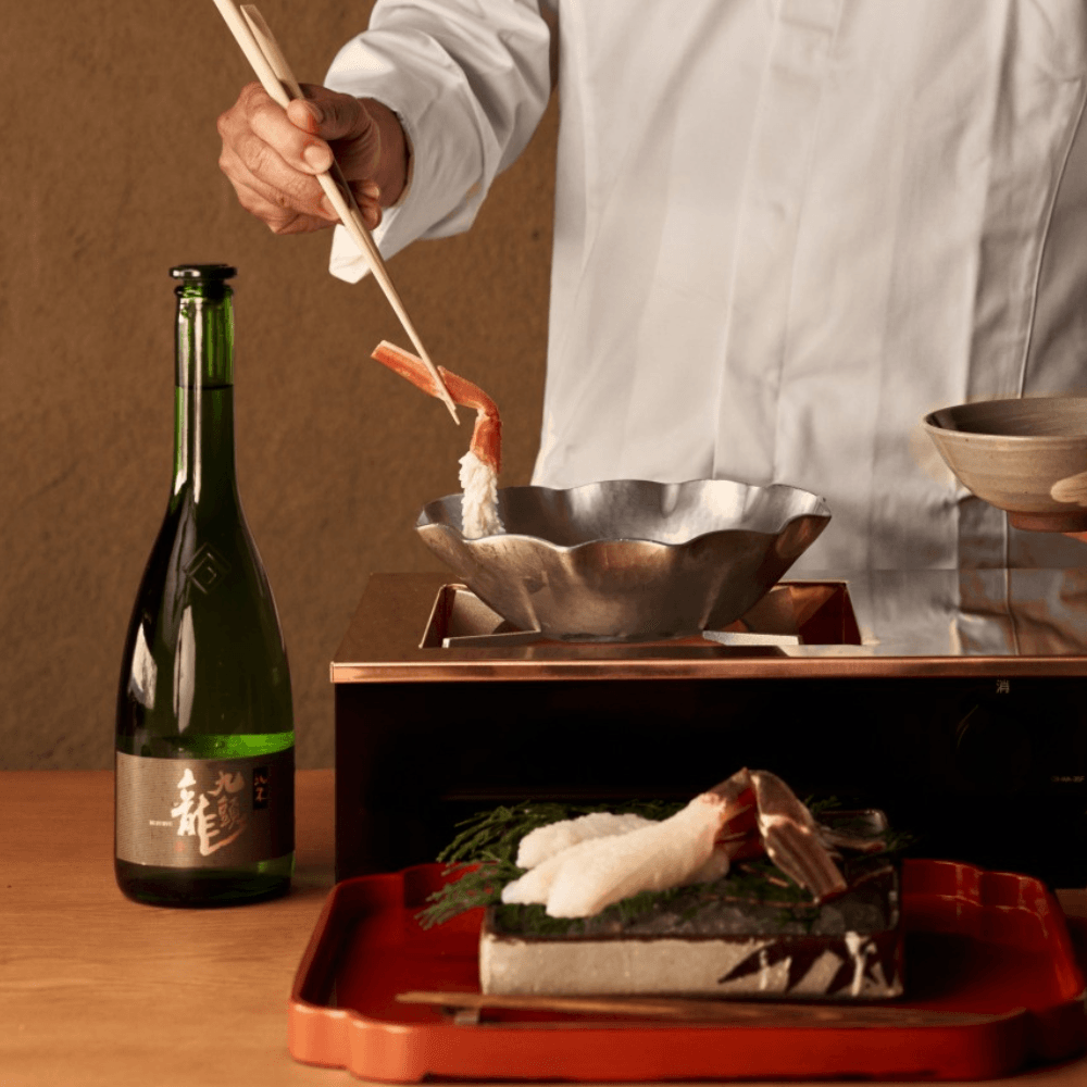Close-up of a chef placing a crab leg into a metal bowl
